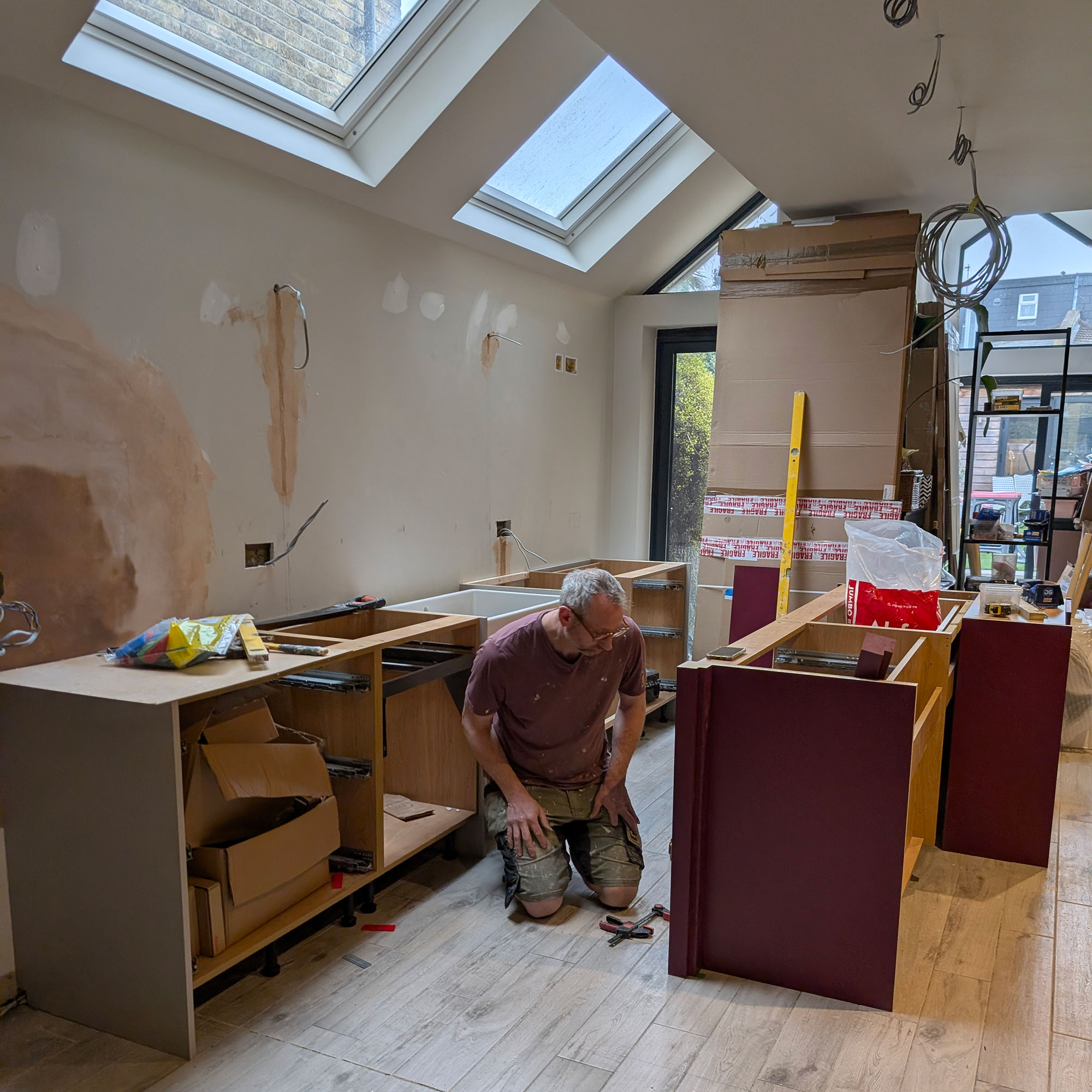 Kitchen being renovated, with man kneeling down looking at newly installed island