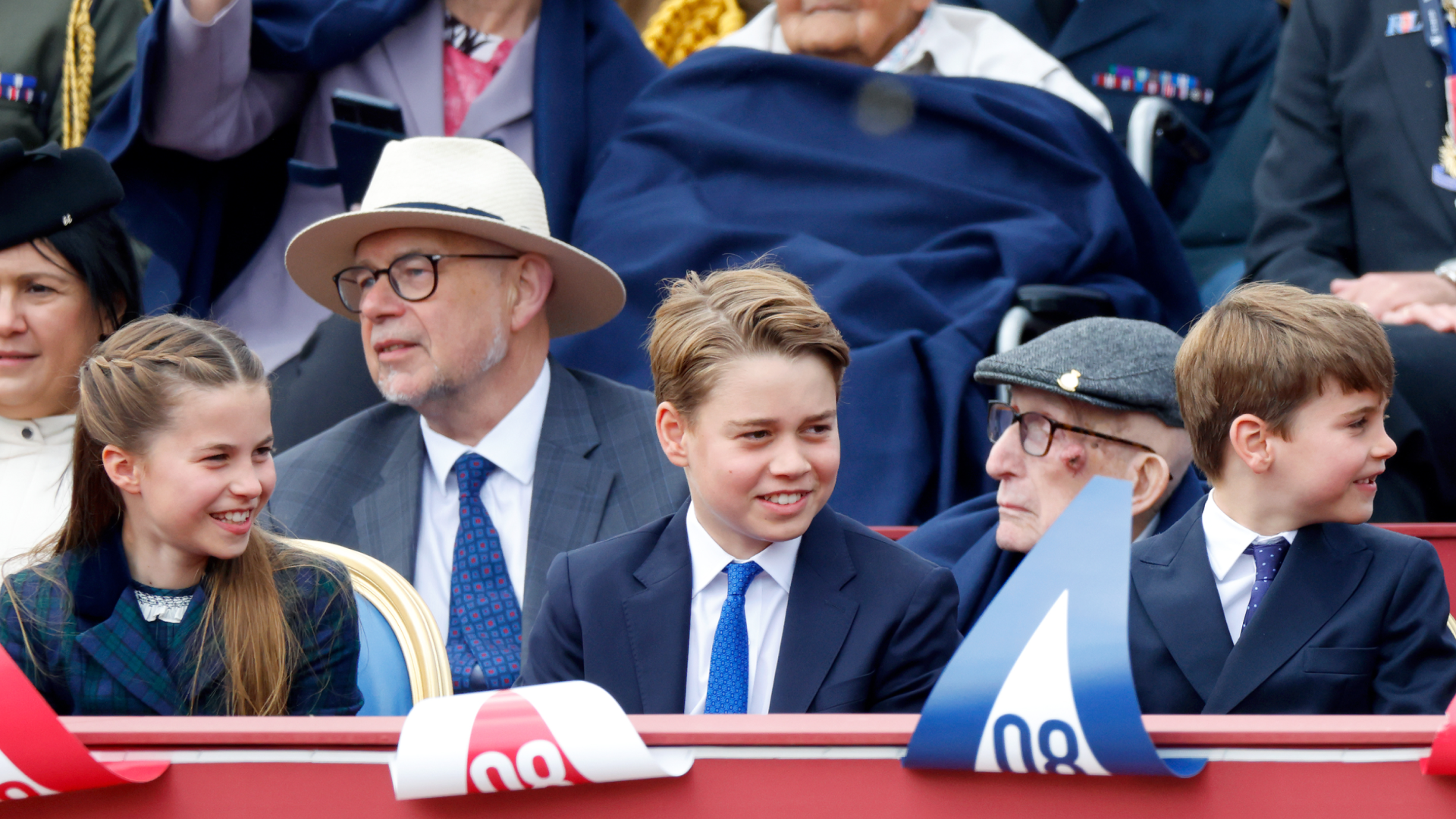 Princess Charlotte, Prince George and Prince Louis sitting in a row in front of red, white and blue bunting