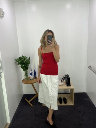 Eliza Huber wearing a red COS tank top and white midi skirt