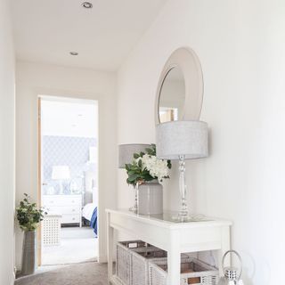 White hallway with console table with matching silver lamps