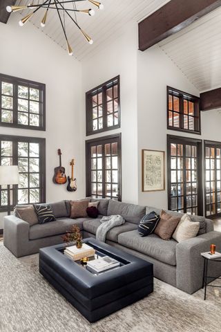A living room with high vaulted ceilings and a grey L-shaped sofa
