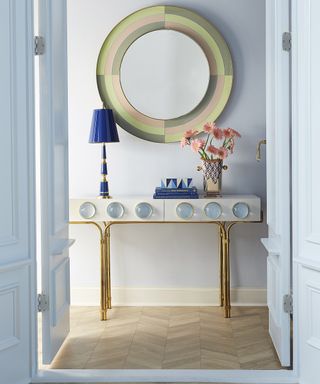 A round hallway mirror idea in pastel shades by Jonathan Adler with pastel blue wall paint decor