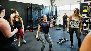 A gym member curling weights in a group