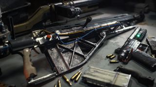 Arc Raiders weapon upgrades: A close-up shot of a makeshift gun with wires attached to it on a workbench, with other guns and ammo scattered around.