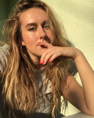 Editor kecantikan Kaitlyn McLintock memakai cat kuku merah di bawah sinar matahari
