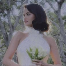 selena gomez wearing a white wedding dress holding a bouquet of white flowers