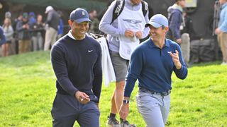 Tiger Woods and Rory McIlroy of Northern Ireland laugh together while walking off the 11th tee box during the first round of The Genesis Invitational