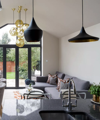 Three different black and gold kitchen light designs above a grey sofa.