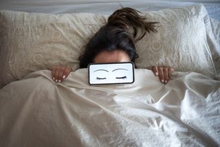 Woman in bed with cellphone, cartoon eyes with big eyelashes: sweet dreams