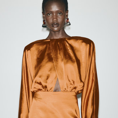 Photo of model wearing orange satin long sleeve dress.