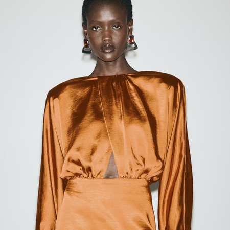 Photo of model wearing orange satin long sleeve dress.