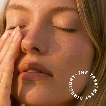 A close-up photo of a model touching her face with her eyes closed