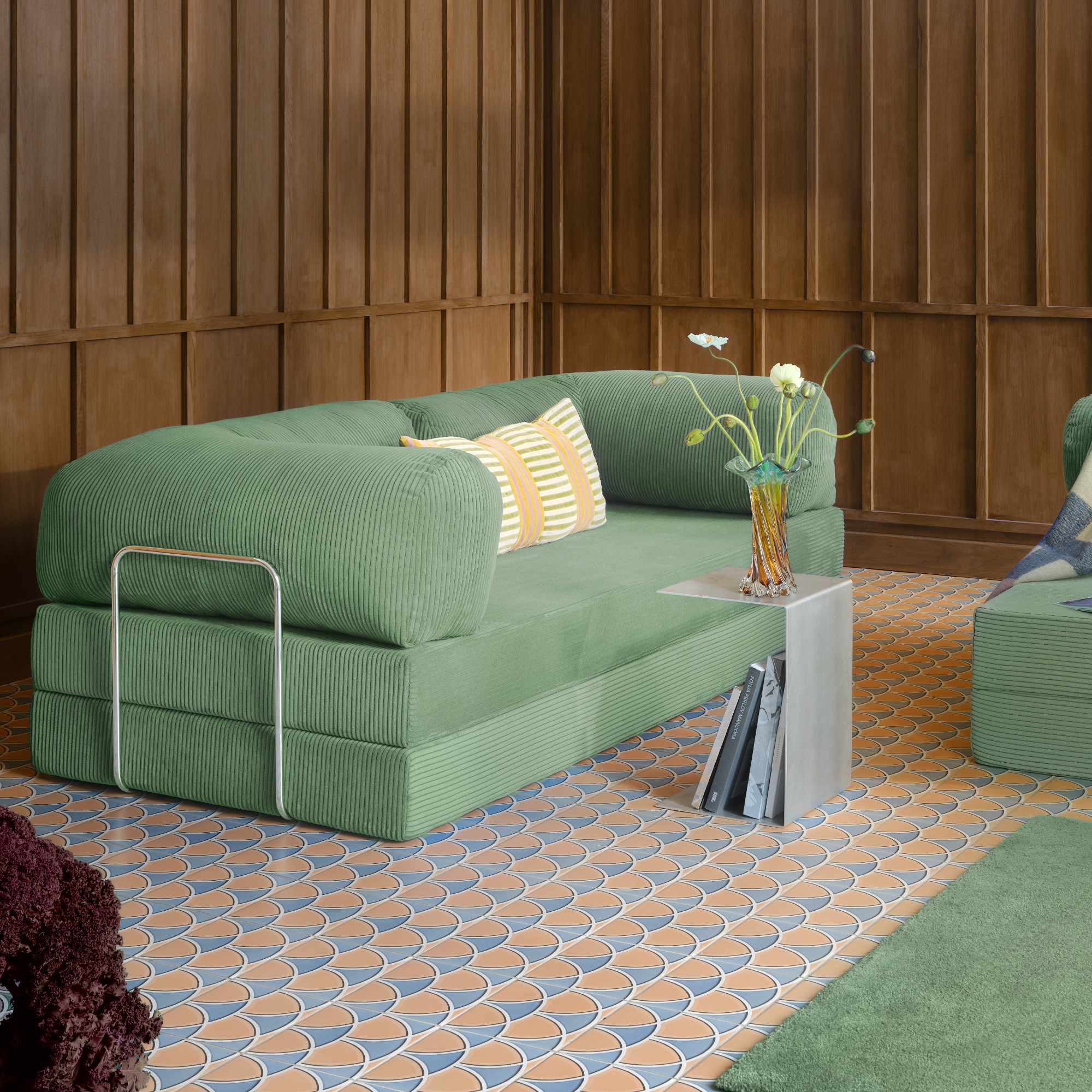The Teddy sofa by OMHU in Sage in a living room with dark wood wall panelling and patterned tiled flooring