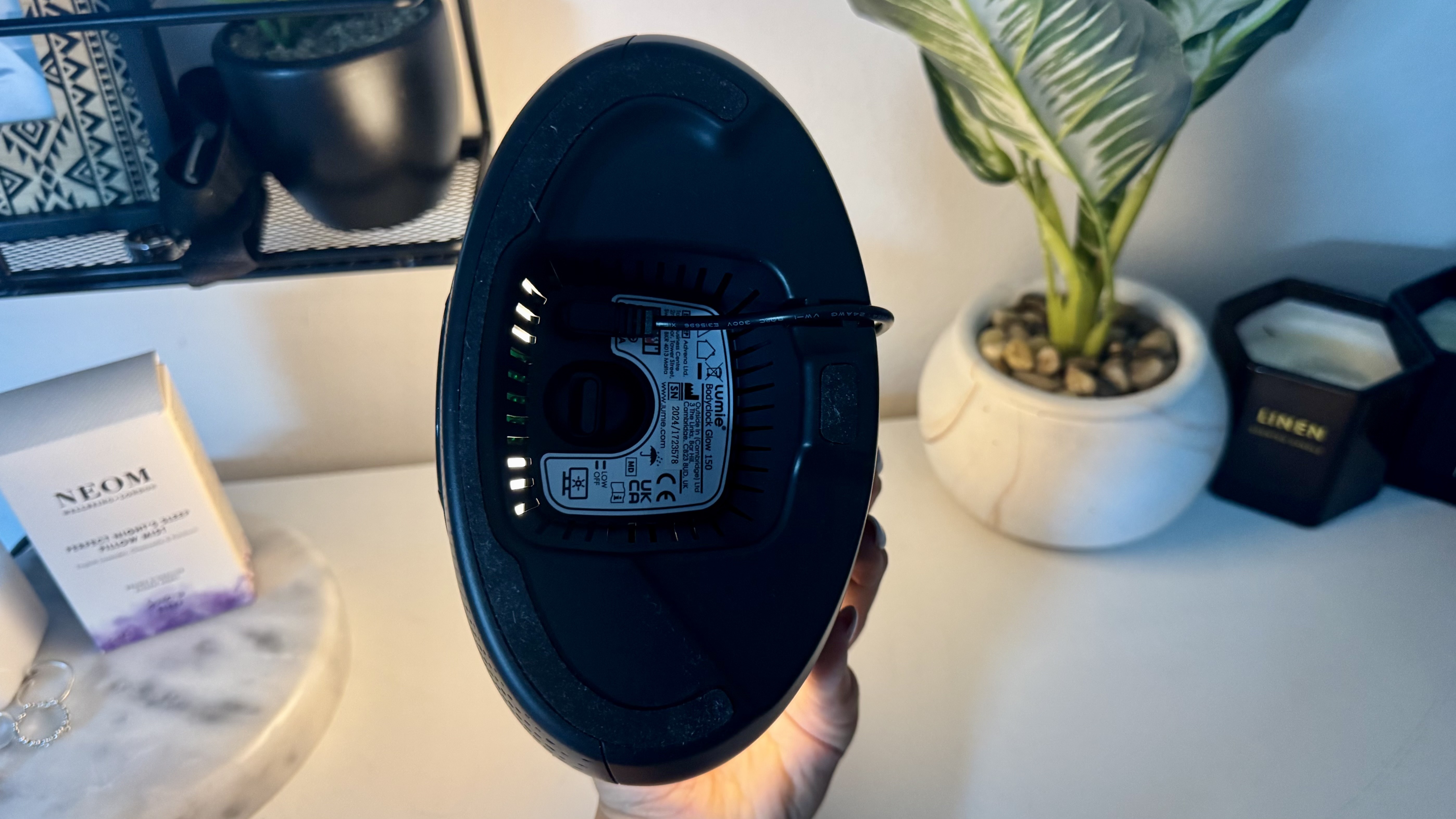 Lumie Bodyclock Glow 150 sunrise alarm clock on bedside table with NEOM pillow spray and plant