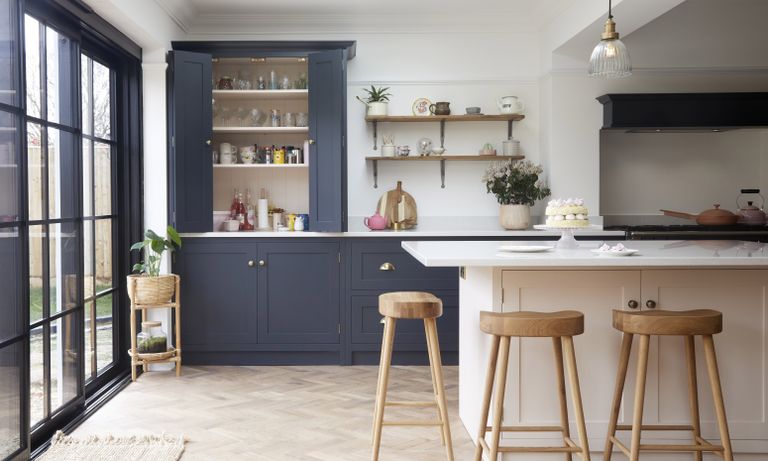 navy shaker kitchen with pale pink island and wooden bar stools 
