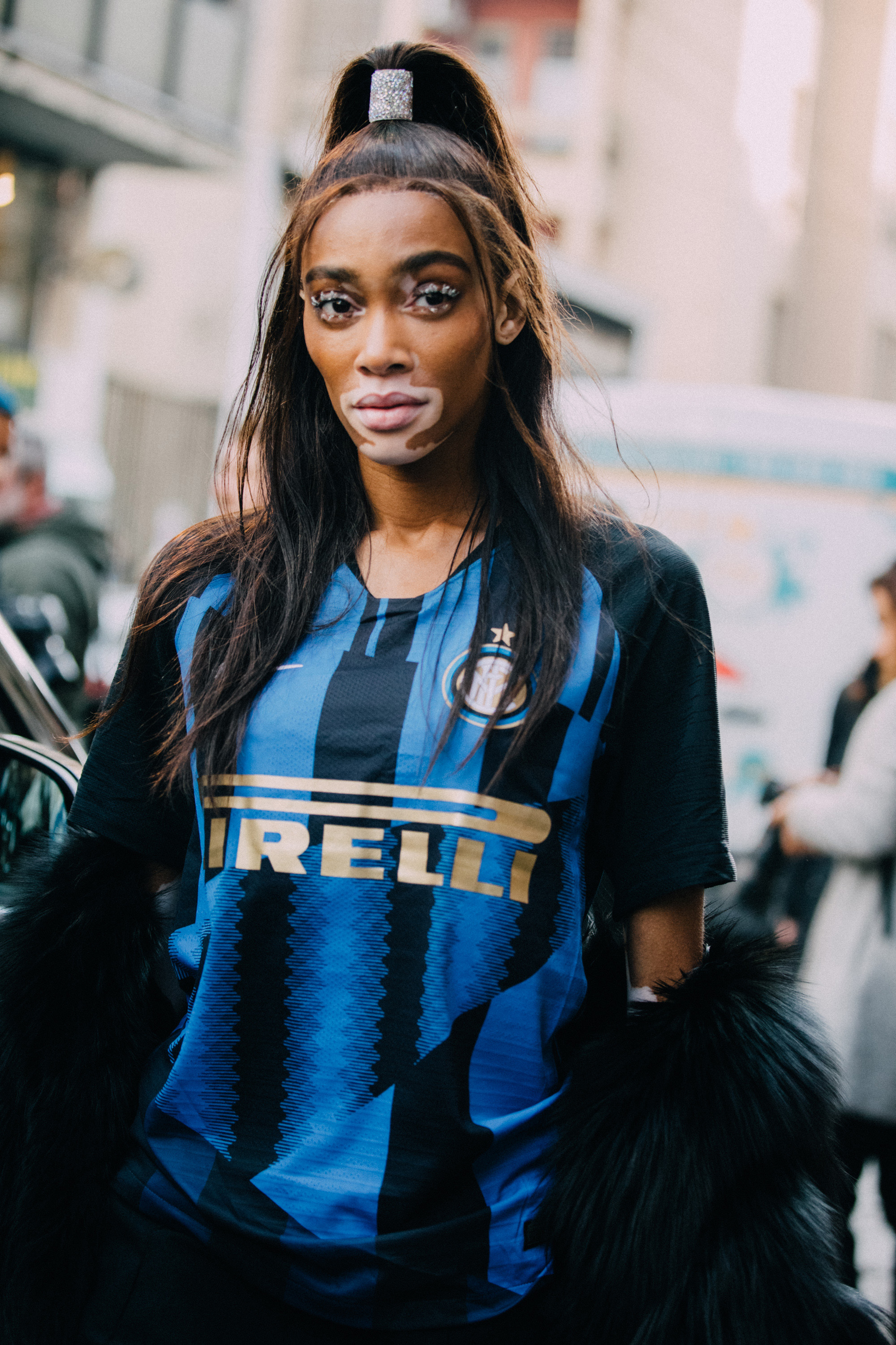 Model Winnie Harlow wears her hair in a high ponytail and wears a blue Pirelli soccer/football jersey after the Byblos show on Day 1 Milan Fashion Week Autumn/Winter 2019/20 on February 20, 2019 in Milan, Italy.