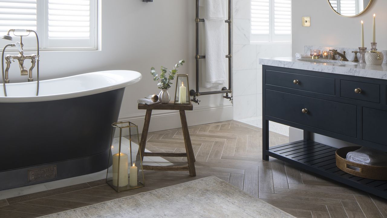 Bathroom with freestanding navy bath, wooden stool and candles