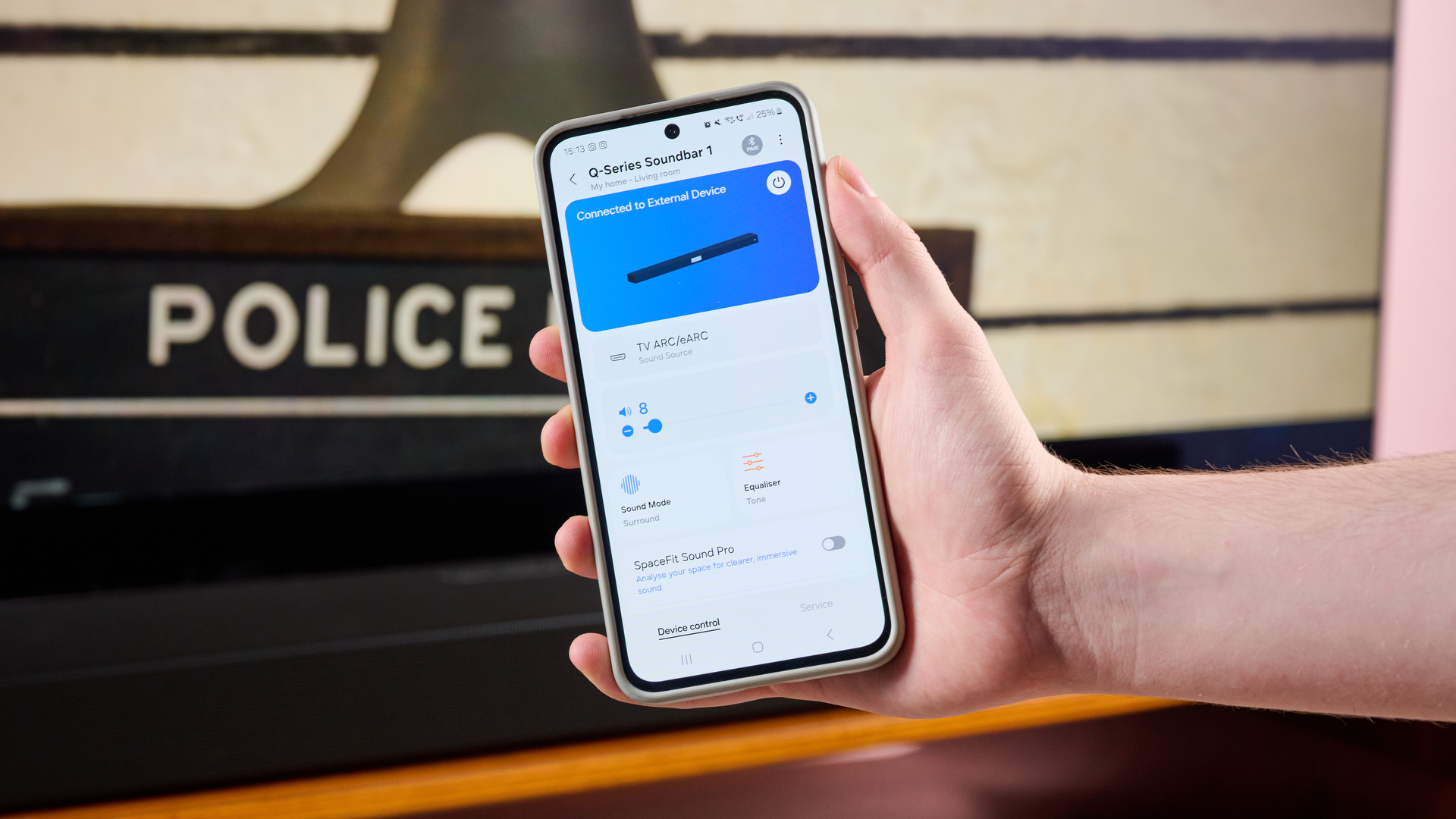 Person holding phone with SmartThings app beside the Samsung HW-Q800F