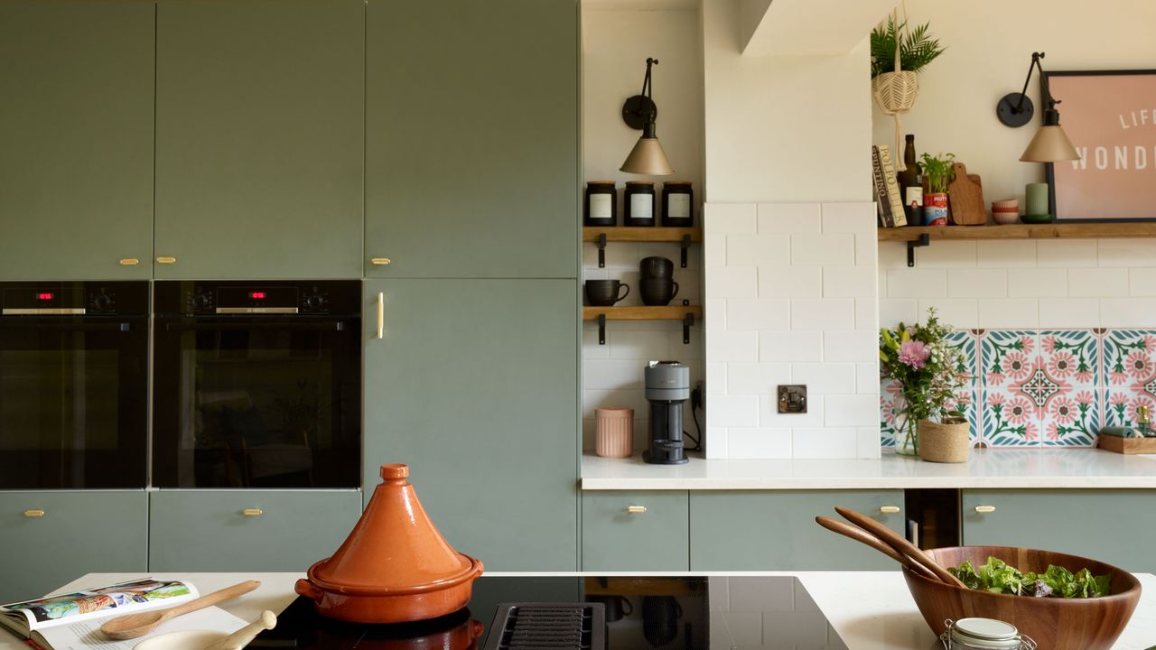 Green/blue cupboards, gold leaf island unit, large patterned tiles above the sink. Wooden dining table, with wooden slatted wall behind