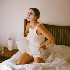 A woman in bed wearing a sheet mask