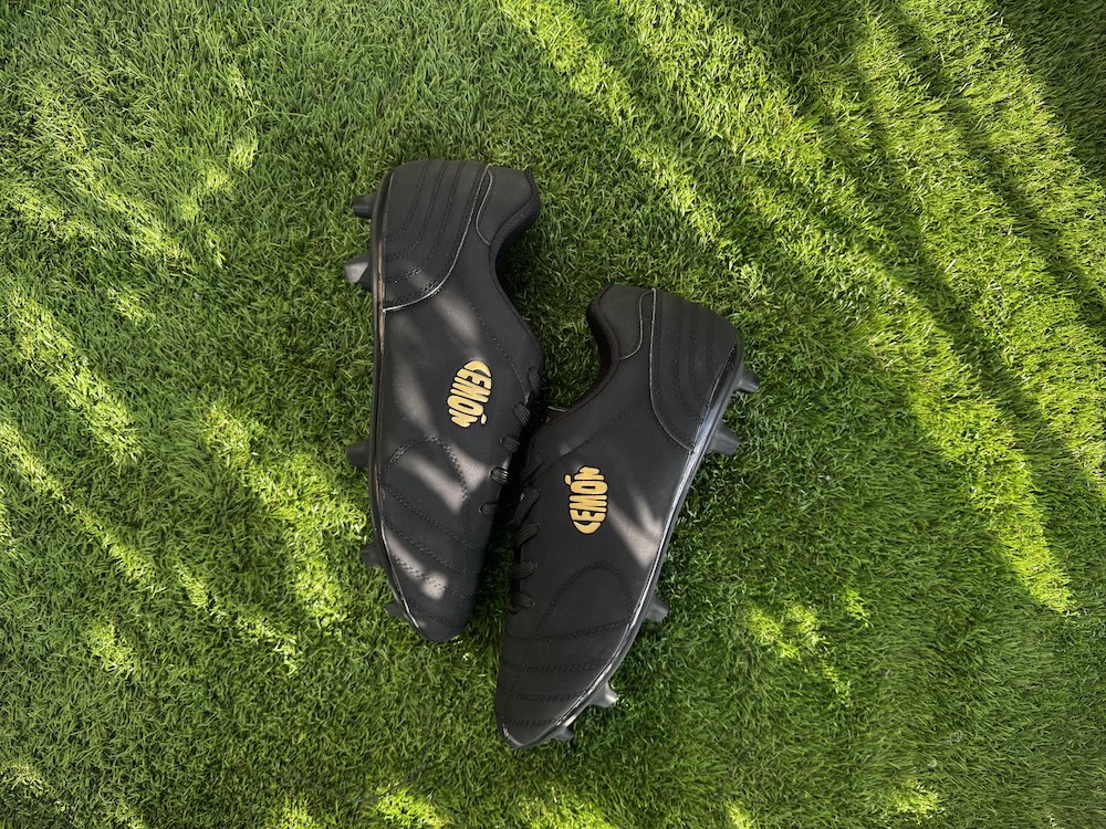 Black Lemon football boots on green grass