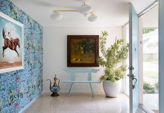 An entryway with blue door, blue chair and wallpaper, all with the background of white