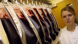 blood transfusion bags hang on a line in front of a woman in white coat