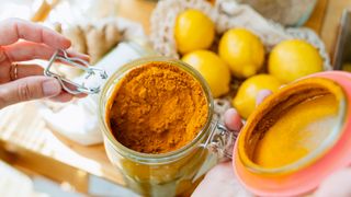 open jar of turmeric with a pile of lemons in the background
