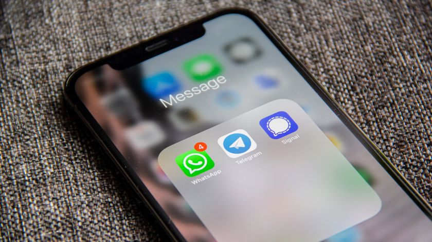 A smartphone on a sofa showing the WhatsApp, Telegram and Signal apps