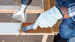 heat gun being used with scraper to remove paint from wood
