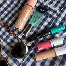 a flatlay of some sunglasses and some of the e.l.f. bestselling make-up products