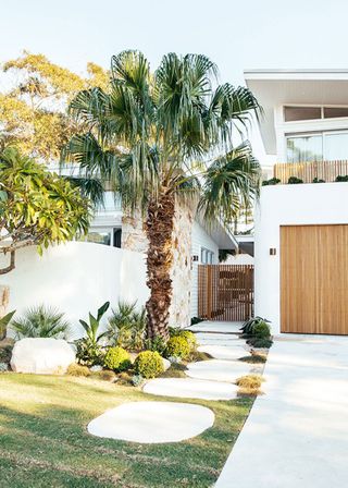 Oversized front walkways ideas with large white paving stones leading to a modern wooden gate.