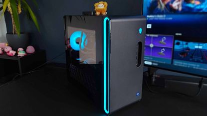 Alienware Aurora R16 PC sitting on black desk at an angle with blue RGB lights on