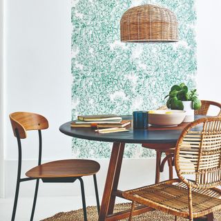 A dining room with a round wooden dining table and mismatched wooden and rattan chairs