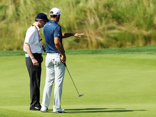 Dustin Johnson talking to a rules official on the 5th green at Oakmont Country Club (2016 US Open)