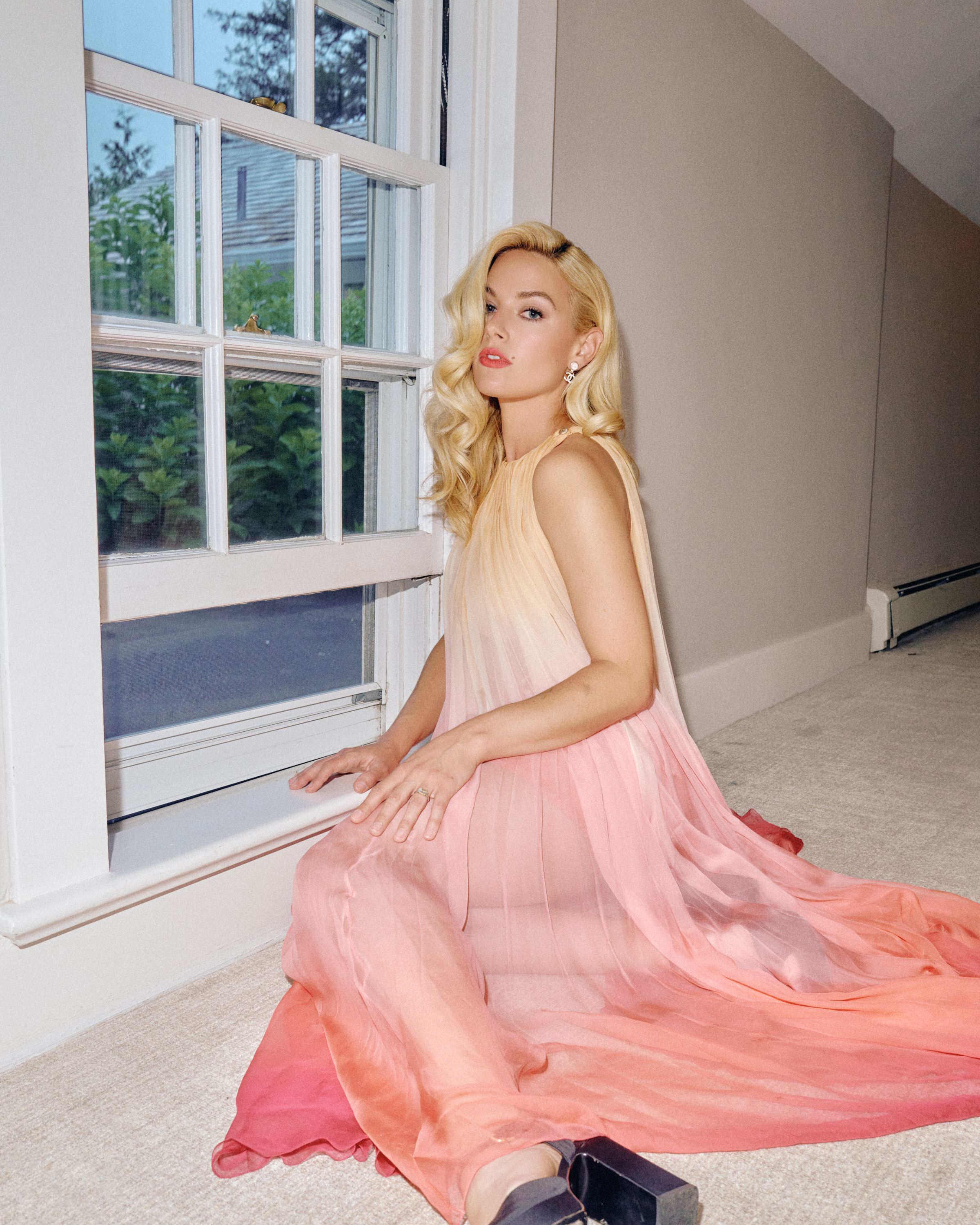 Ashe sits down in her Hamptons House wearing. a Chanel sheer dress