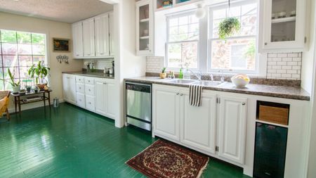 A classic white kitchen with green painted wood floor