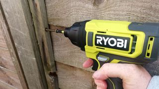 The 18V ONE+ Cordless Impact Driver screwing in a 120mm screw into a wooden post