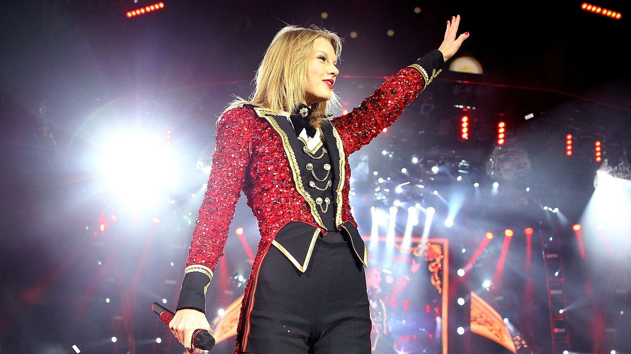 Taylor Swift on stage in a ring leader inspired outfit waving to her fans.