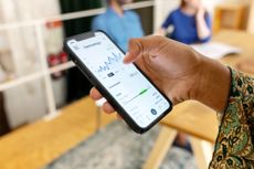 Close-up of a woman trading stock market on smartphone with stock market financial screen