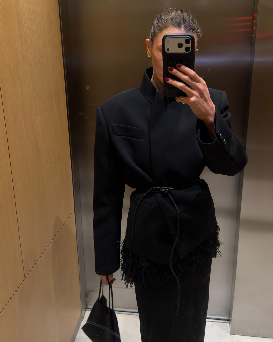 Influencer @cocoschiffer wears a black high-neck blazer with a leather string belt.