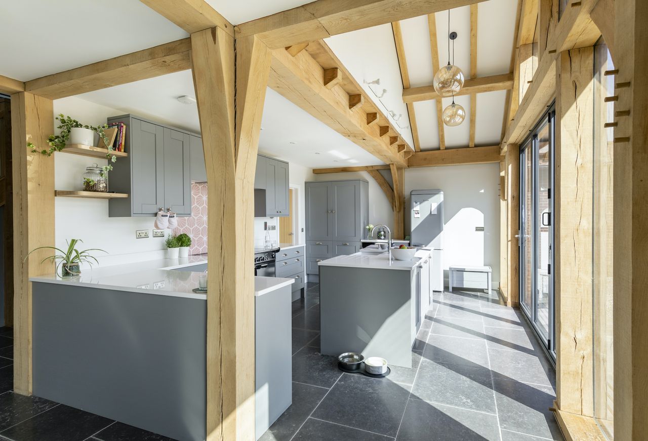 The kitchen features a double-height apex with pendant lights bringing a drama to the pared-back space.