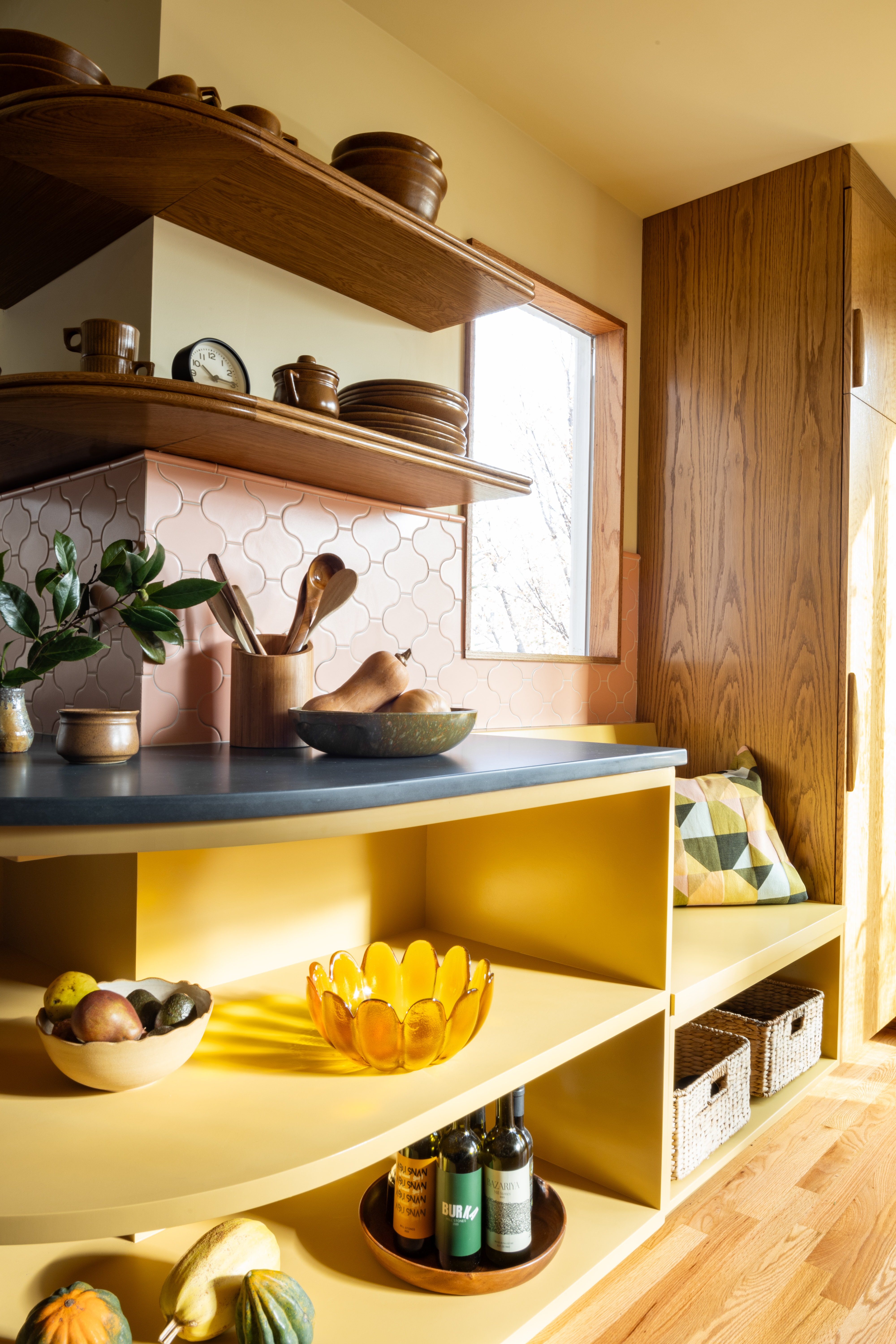 A kitchen with a rounded edge, painted yellow cabinets and wood flooring