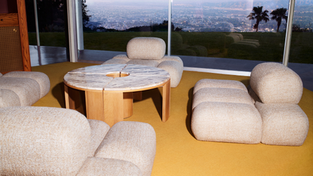Kelly Wearstler x H&M Home modular organically shaped chairs styled in a Los Angeles living room with large windows, lemon yellow carpet, and a circular marble sofa table.