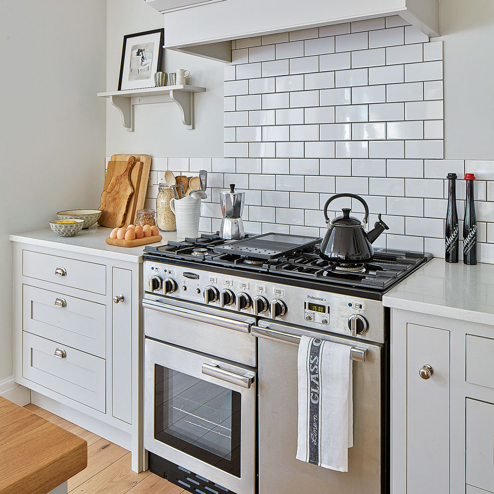black whistling kettle on chrome gas stove in white kitchen