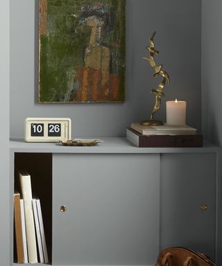 A light blue cabinet and wall with a clock, painting and gold sculpture