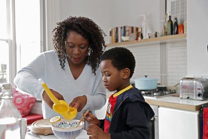 Mother helping a young boy in the kitchen with cooking