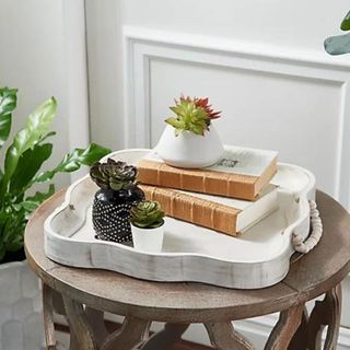 A wooden storage tray on a side table with books and potted succulents