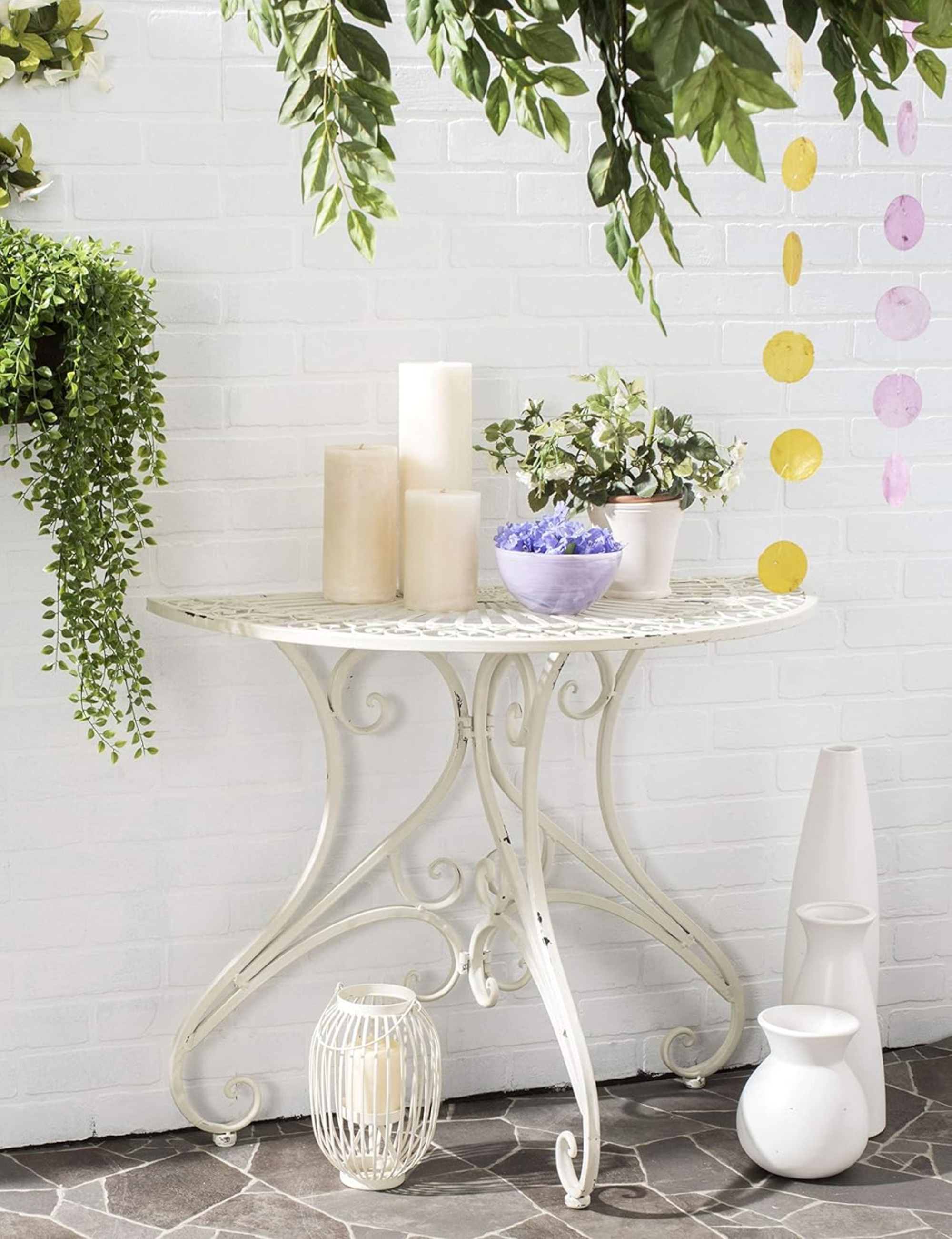 Airy antique-style outdoor semi-table styled on a stone-floored patio with white painted bricks