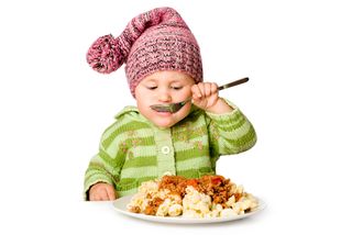 A child eats food from an adult-sized plate